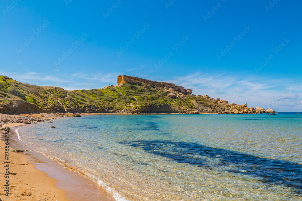 Obraz premium Clay Cliffs in Malta on a sunny day, featuring striking reddish rock formations, rugged coastline, and the deep blue Mediterranean Sea creating a dramatic and scenic landscape.