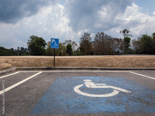 Accessible parking space with wheelchair symbol and sign, empty disabled parking spot in outdoor area, inclusivity and accessibility concept, Thai words say disabled parking