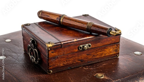 A fine writing instrument rests upon a vintage wooden box. The box, tarnished with aged accents, is placed atop a leather surface