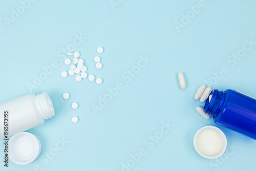 Canvas Print Top view of two bottles with scattered pills on a light blue background