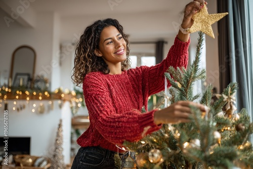 Woman hanging ornament on Christmas tree indoors