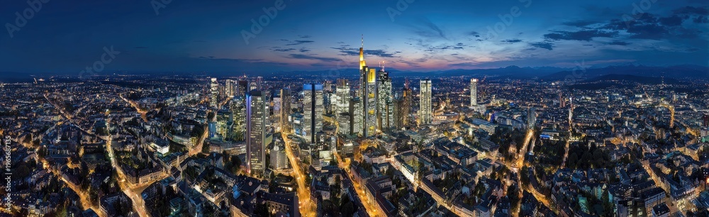 Obraz premium Panoramic aerial view of a city skyline at dusk, showcasing numerous illuminated skyscrapers