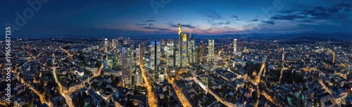 Panoramic aerial view of a city skyline at dusk, showcasing numerous illuminated skyscrapers