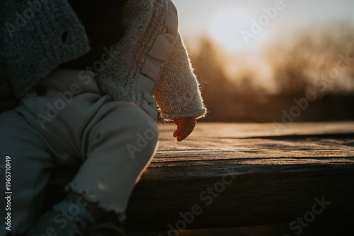 Canvas-taulu Détail d'une petite main d'enfant effleurant une table en bois au soleil couchan