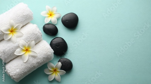 Elegant Spa Setting with White Towels, Black Stones, and Frangipani Flowers on Aqua Background