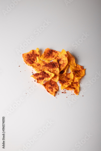 Heap of dried pumpkin slices, dry vegetable chips pile with pepper, paprika on white background. Advertising banner, copy space. Product presentation.