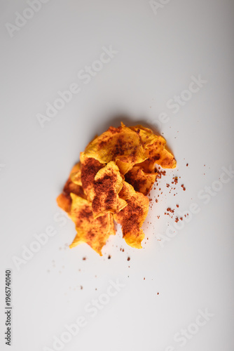 Heap of dried pumpkin slices, dry vegetable chips pile with pepper, paprika on white background. Advertising banner, copy space. Product presentation.