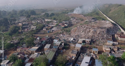 Aerial fly over view. Burning rubbish causing greenhouse gas, contributor to climate change.  Extreme Poverty. People living alongside dumpsite struggling to survive through waste picking.