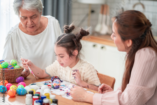Fotografía Three generations gather around a table full of colorful Easter eggs and paint, each carefully decorating their own egg in a joyful and creative family tradition