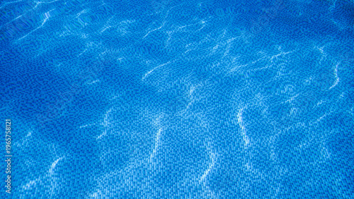 Background picture. Swimming pool bottom ripple and with waves background. Rippling blue water in swimming pool with blurry tile pattern at the bottom.