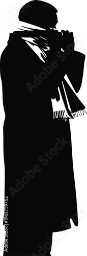 A person in a long coat and scarf plays a musical instrument on the street at night.