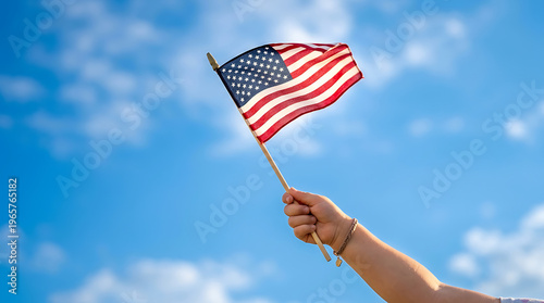 Child Hand Holding Small American Flag Against Blue Sky