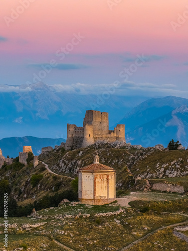 Aerial view of the medieval fortress of Rocca Calascio and the octagonal chapel of Santa Maria della Pieta on a mountain ridge at sunset Calascio, Abruzzo, Italy.