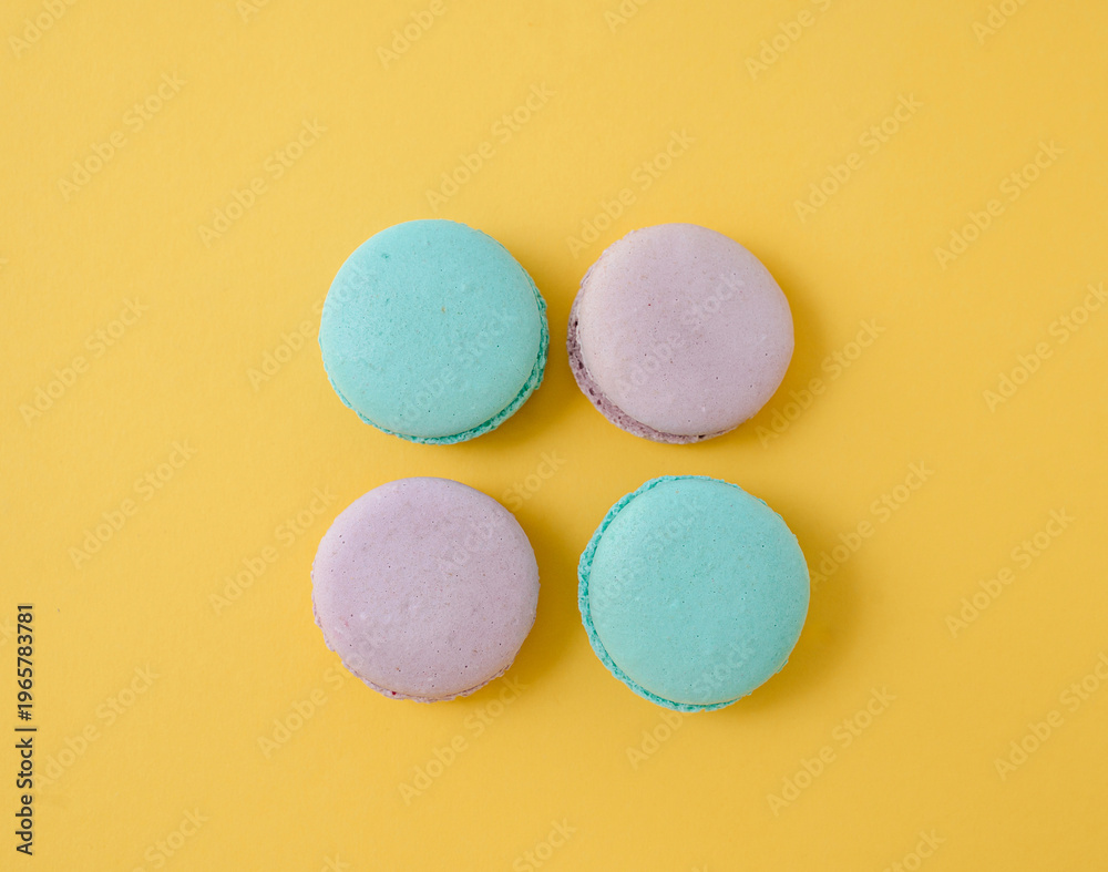 Obraz premium Assorted French macarons on bright yellow background, sunny and cheerful food composition for bakery banner