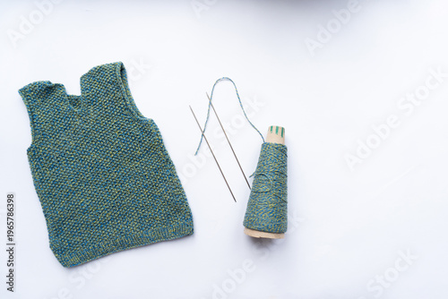 Waistcoat, thread, needles are on white background