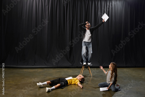 Tablou pe pânză Stylish male tutor guides young students in creative theater performance fun