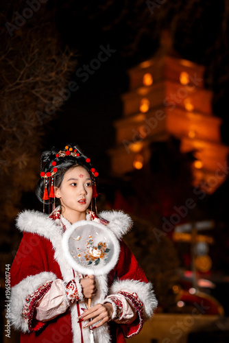 Red robed woman holds a fan and goes on a night tour of the Big Wild Goose Pagoda in Xi'an