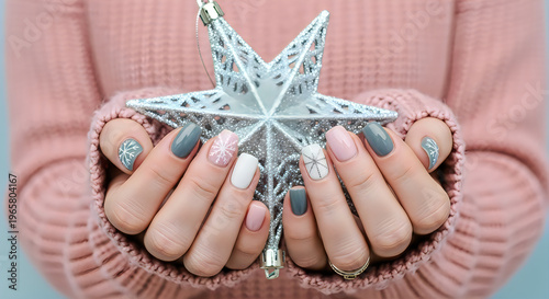 Woman holding a silver glittery star christmas ornament with painted nails
