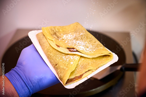 Man hand holding a Romanian pancake on electric grill
