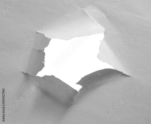 Isolated hole in newsprint with torn edges and paper texture.