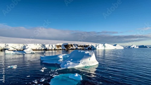 Aerial view of a glacial landscape with icebergs floating on blue water under a clear sky