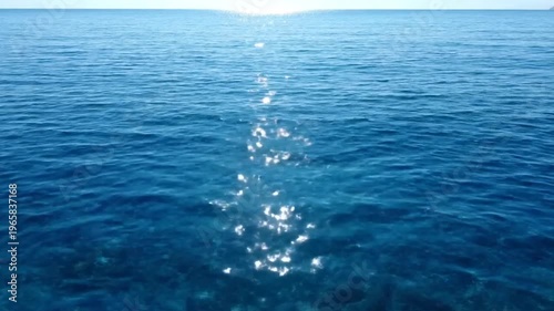 The gentle sunlight reflects its golden rays onto the calm blue sea surface,4k