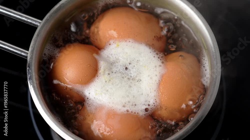 Bubbling hot water in a saucepan with boiling chicken eggs on the stove
