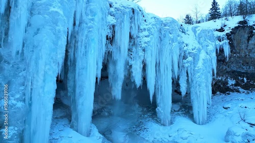 Stunning video capturing the breathtaking view of large icicles hanging from a snowy cliffside in a cold winter landscape