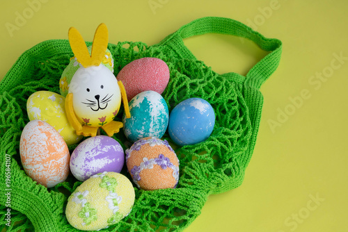Easter eggs in a string bag on a white table. The concept is the Orthodox holiday of Bright Easter