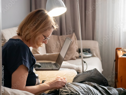 Принти на полотні Woman sewing clothes while sitting on sofa in living room