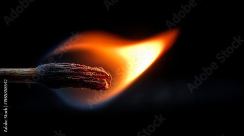 A close-up of a matchstick igniting with a bright orange flame against a dark background.