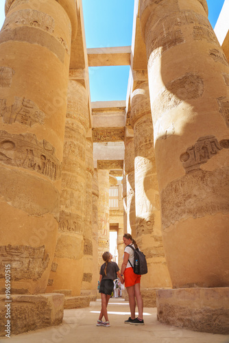  Egypt - karnak hypostyle hall columns in the temple at luxor thebes and happy tourist girls - mother and daughter on vacation.
