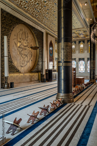 Interior of ornate mosque with golden calligraphy walls and patterned carpet in Doha Qatar