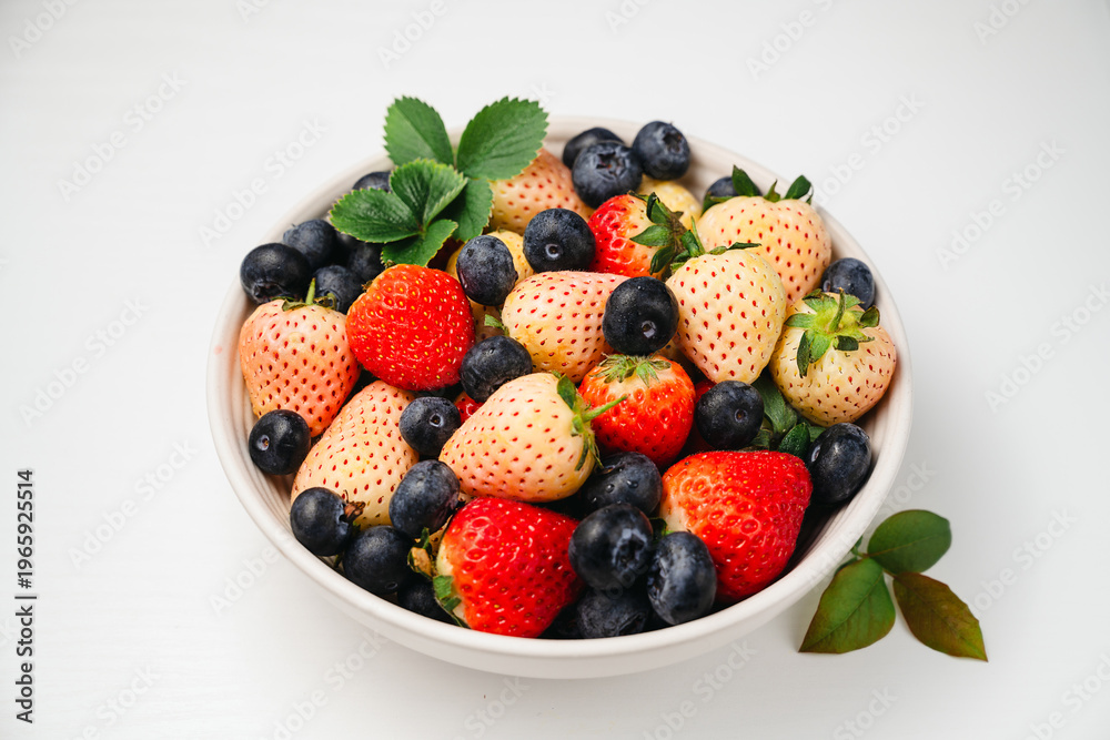 Obraz premium Antioxidants and vitamins. Red and pink strawberries and fresh blueberries in a bowl, top view