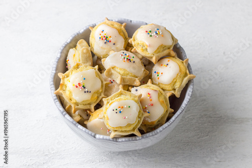 Traditional Sardinian ricotta cheese cookies with sugar glaze and sprinkles in ceramic bowl on white background