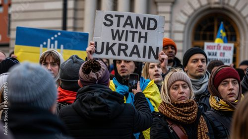 Crowd of people holding signsabout Ukraine war and flags in front of a building.
