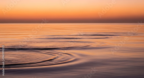 Gentle ripples form concentric circles on calm water at sunset