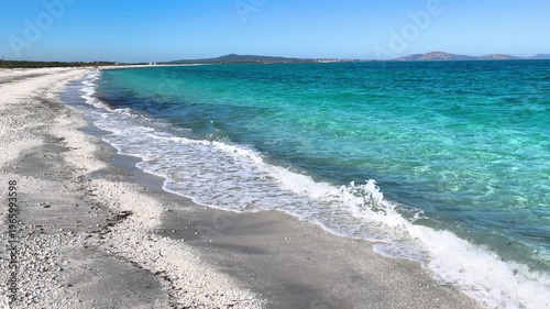 Slow motion view of a beach with clear turquoise water in Sardinia. Gentle waves and transparent sea create a relaxing summer coastal scene in a Mediterranean landscape.