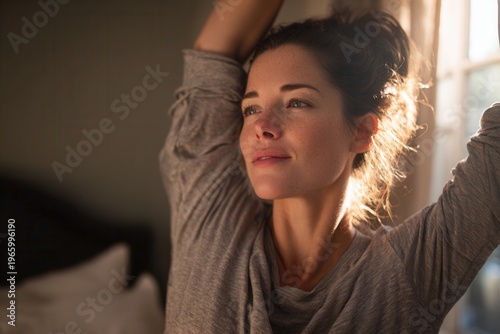 Smiling woman stretching arms enjoying peaceful morning sunlight at home