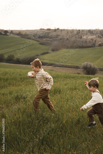 Obraz na plátně Two boys running through a field, laughing and chasing each other, vintage child
