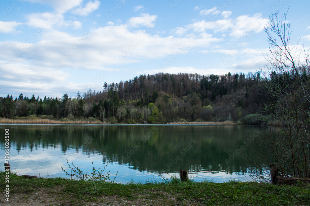 Fototapeta premium Wide lake landscape with forest reflection and blue sky