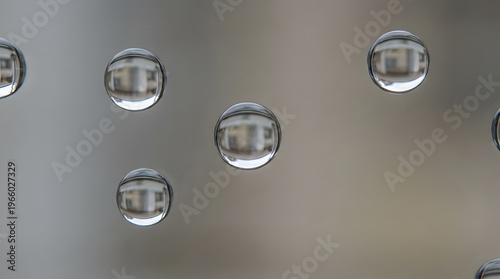 Water droplets on glass create a dreamy effect, blurring a tranquil blue green landscape in the background. Suitable for nature themed designs.