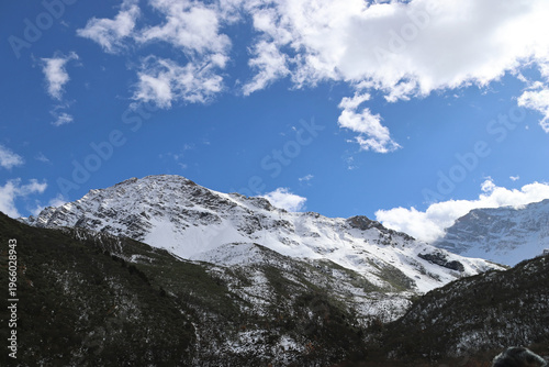 Autumn scenery of Xuebao Peak (Xuebao Snow Mountain) in the Minshan Mountain with dramatic clouds and forest in a sunny day, Songpan County, Sichuan Province of China