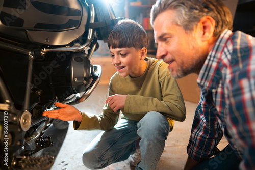 Fotografía A father and son work together on a motorcycle in a garage