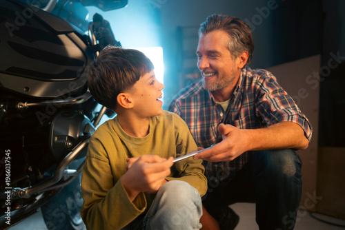 фотографія A father and son spend time in a garage working on a motorcycle