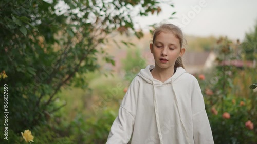 White girl closeup in garden soft pensive expression hoodie detail braided hair framing face hands on basket contemplative mood nature student daydreamer poet persona shallow focus warm evening light