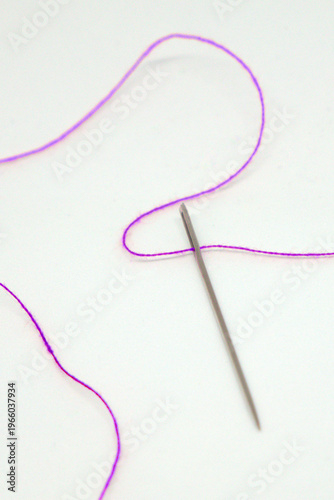 Purple needle and thread on white background 