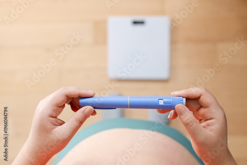 Bild auf Leinwand A horizontal close up of a young woman holding pre-filled pen injector with sema