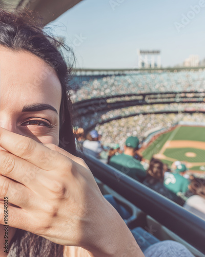 Young woman covering face with hand at baseball stadium