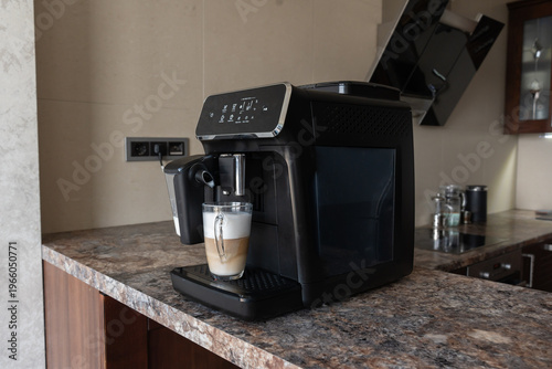 A coffee machine with a cup of cappuccino coffee on the kitchen counter